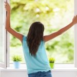 woman opening windows to improve indoor air quality