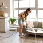 pretty young woman cleaning coffee table with pp-duster in modern open space kitchen