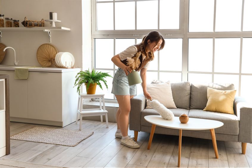 pretty young woman cleaning coffee table with pp-duster in modern open space kitchen